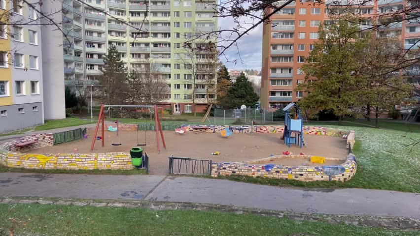 Playground area, featuring swings and a sandy zone, is conveniently located amidst residential buildings at autumn in Europe. No people