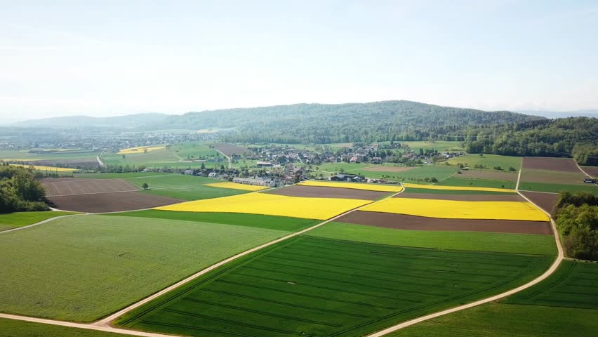 Aerial view of pattern of agri fields vibrant crops near Habsburg medieval village showcasing the beauty of nature in the countryside Aargau, Switzerland drone flying over