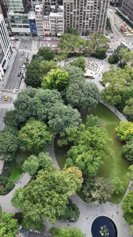 A captivating vertical orientation drone circle shot of Madison Square Park and E 25th Street in New York City, showcasing the iconic greenery amid Manhattan
