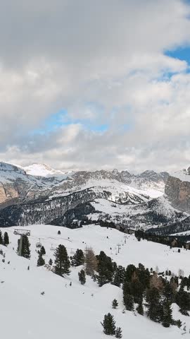 View of a ski resort piste with people skiing in Dolomites in Italy. Ski area Belvedere. Canazei, Italy. Horizontal camera pan