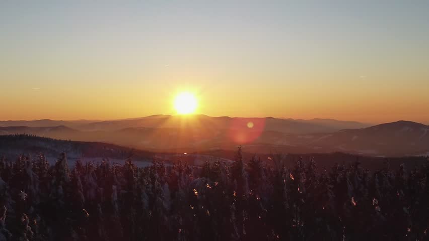 Golden sunset over snow-covered mountains in the Beskidy Mountains, Beskid Slaski, Poland, with a warm winter glow.