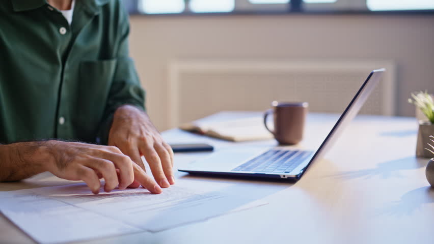 Manager checking business documents at work desk closeup. Successful businessman rejoicing financial win looking laptop screen in office. Emotional man entrepreneur celebrating success at workplace.
