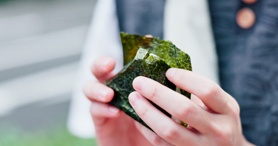 Japan person, hands and rice ball for food, culture and traditional snack with holiday, taste and seaweed. Nutrition, hungry and eating onigiri for local meal, lunch and breakfast on weekend break