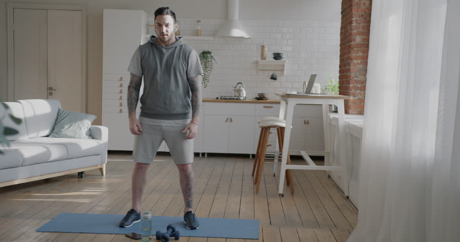 Young motivated sportsman training indoors at home doing physical exercises focused on workout. Active lifestyle and people concept.