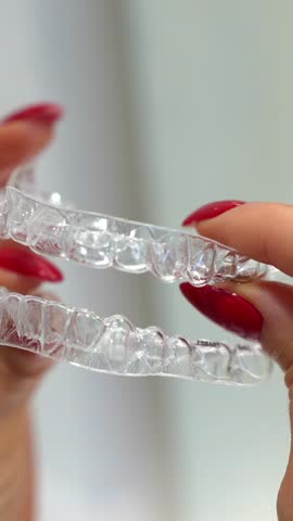 Close-up of the hands of a caucasian woman holding invisible retainers