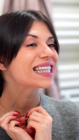 Caucasian Woman positioning transparent dental aligners on her teeth in bathroom at home