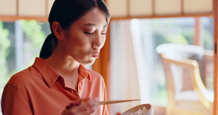 Eating, food and Asian woman with crispy rice at lunch for in home with healthy meal and nutrition. Hungry, person and dish for diet, wellness and taste with chopsticks and snack at house in Japan