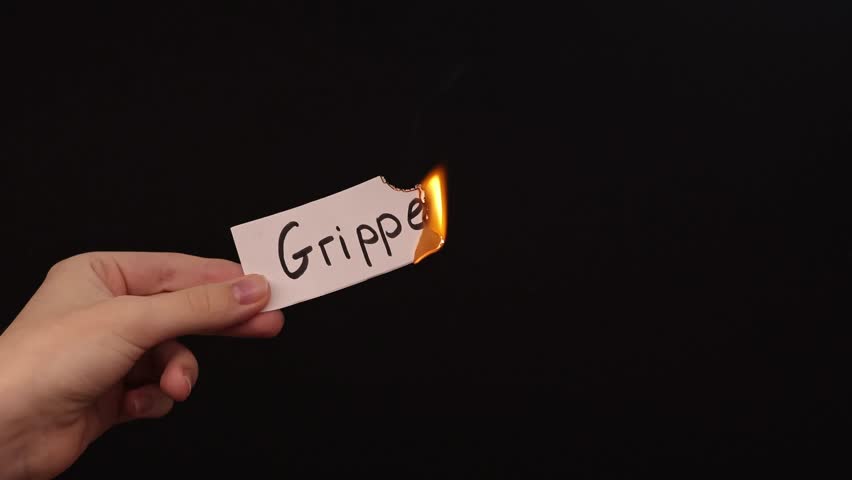 Burning a piece of paper with the word "Grippe" written on it, against a black background