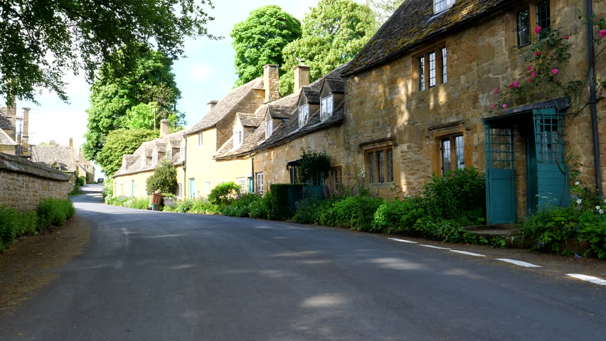 Yellow brick house terrace in Snowshill, small village in Cotswolds, panning shot on a sunny summer day.