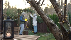 Couple Preparing Festive Winter Decorations: Adorning a Rustic Wooden Arch with Pine Branches and Twinkling Lights in a Cozy Outdoor Yard Setting - Powered by Shutterstock - Get 15% off with code: PIKWIZARD15