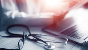 Doctor Reviewing Medical Records or Test Results: Close-up of a Stethoscope, Glasses, and Laptop in a Healthcare Setting, Highlighting Precision and Technology in Modern Medicine - Powered by Shutterstock - Get 15% off with code: PIKWIZARD15