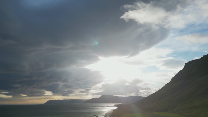 Sunbeams shining through dramatic clouds over a beach and mountains in Iceland.