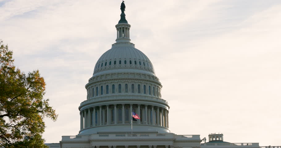 Close up of US flag flutters in the wind in slow motion in front of the Capitol Cupola