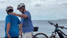 Caucasian senior couple of cyclists wearing helmets enjoying healthy lifestyle riding with electric bicycles along the seacoast. Authentic senior retired life concept. Horizon over the sea - Powered by Shutterstock - Get 15% off with code: PIKWIZARD15