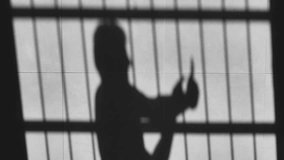 shadow of prisoner man using phone behind the jail bars reflected on the floor,silhouette of kidnapped person using mobile device to communicate outside - Powered by Shutterstock - Get 15% off with code: PIKWIZARD15