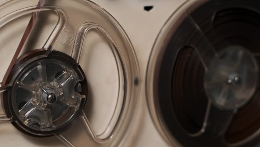 Detailed close up of vintage audio tape reels spinning. Ideal for retro themed projects needing a feeling of nostalgia and history. Great background texture.