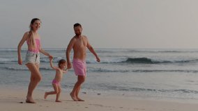 Young family walk on the beach in beautiful Island. Happy family spend nice time ocean shore. Parents walk with daughter during sunset. - Powered by Shutterstock - Get 15% off with code: PIKWIZARD15
