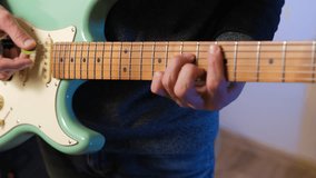 Close-up of talented male musician passionately strums a mint electric guitar, crafting original melodies and exploring songwriting in a cozy indoor setting, creative process - Powered by Shutterstock - Get 15% off with code: PIKWIZARD15