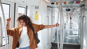 Woman enjoying music and dancing in subway in slow motion.   Young woman wearing headphones dances joyfully inside an empty subway car, embracing the freedom of movement and music - Powered by Shutterstock - Get 15% off with code: PIKWIZARD15