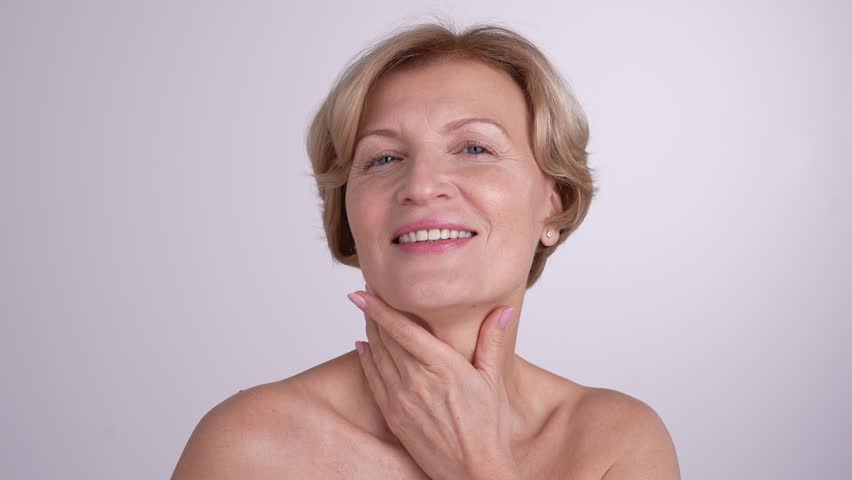 Portrait of a mature lady touching her neck and shoulders. Graceful female embracing her natural beauty and positive aging. 4k high res