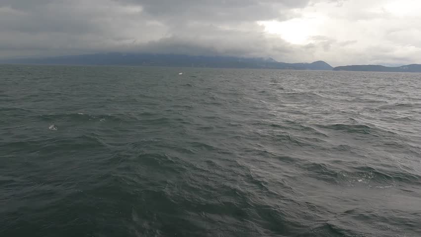 Cloudy, gloomy sky with a light storm, windy weather. Ocean against the clouds, light rain. The sun is peeking through the clouds. Horizon 2