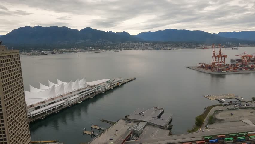 Timelapse, Vancouver in cloudy weather. Ship sails across the strait. Canada Place. View of the mountains. Port cranes.