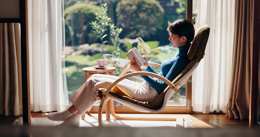 Chair, tea or Asian woman in house reading book for rest break or novel to relax in Japan. Chilling, comfortable or Japanese person drinking beverage with fiction story, or peace for fantasy or hobby