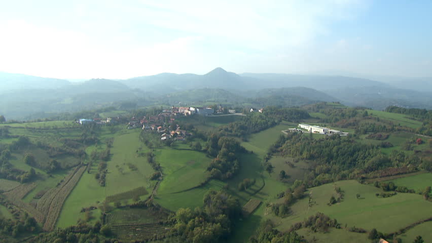 Flying over scenic green hills and valleys in rural area. Aerial helicopter