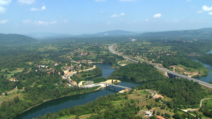 Aerial helicopter shot of a scenic road, highway and bridge across a river
