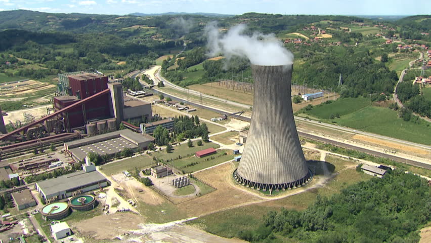 Aerial shot of a Power Plant and its cooling tower with steam rising from it and