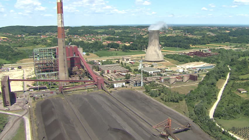 Aerial shot of coal fields and a Power Plant with its cooling tower with steam