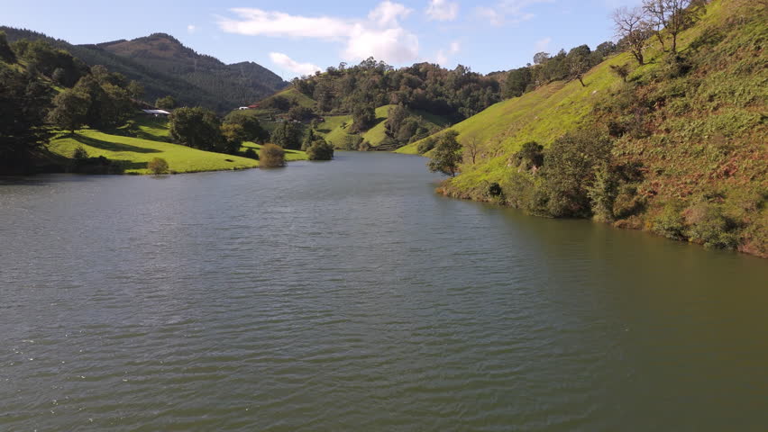 A drone scenic view of Loiolako lake with lush green hills under clear sky in Basque Country, Bilbao, Spain