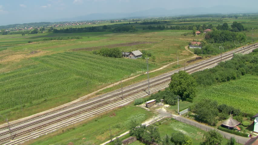 A low altitude aerial along railway in rural area with train passing by