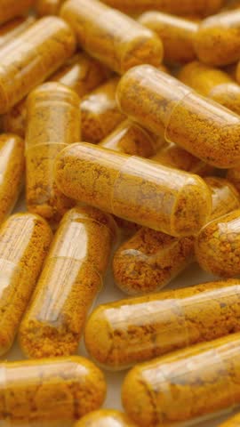 Orange capsules of turmeric dietary supplement with pepper. Capsule collection on white background, spinning to rhythm health. Path to Healthy Life: Pharmaceutical Industry in Production of Capsules.