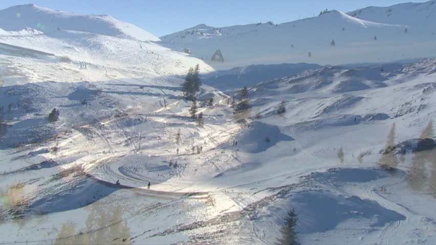 Snow peaks of the mountain Jahorina with bright sun shining over and people