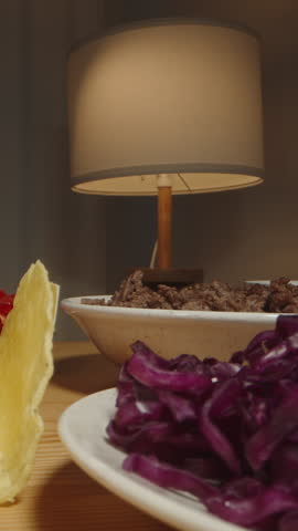 Vertical video. Hand Adds Tomato Sauce to a Taco Shell, Preparing a Delicious Meal with Various Ingredients on the Table. Dolly slider, close up.