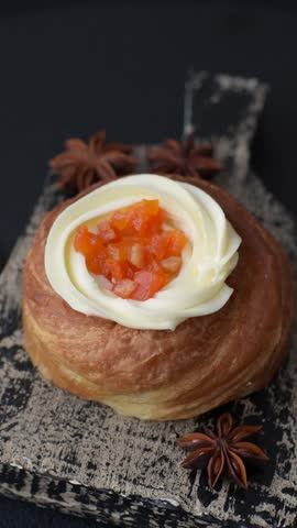 Sweet dessert danish covered with white cream and citrus, with cream filling on a dark concrete background