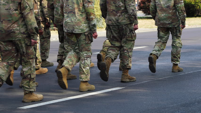 Field soldiers wearing camouflage and carrying rifles marching synchronized. Military parade