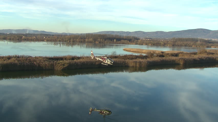 Aerial shot of a helicopter flying over the water