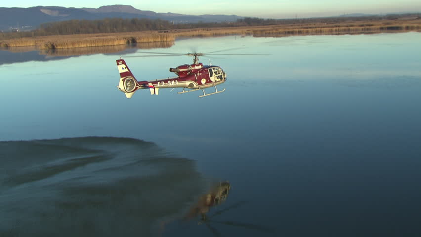 Aerial shot of a helicopter flying very close to the water surface