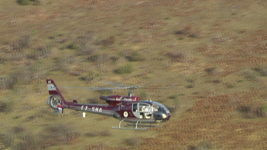 Aerial shot of two helicopters flying close together low over a mountain