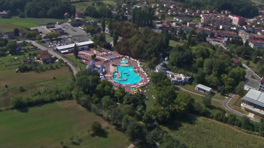 Aerial helicopter shot of a pool with swimmers. Zooming in and out.