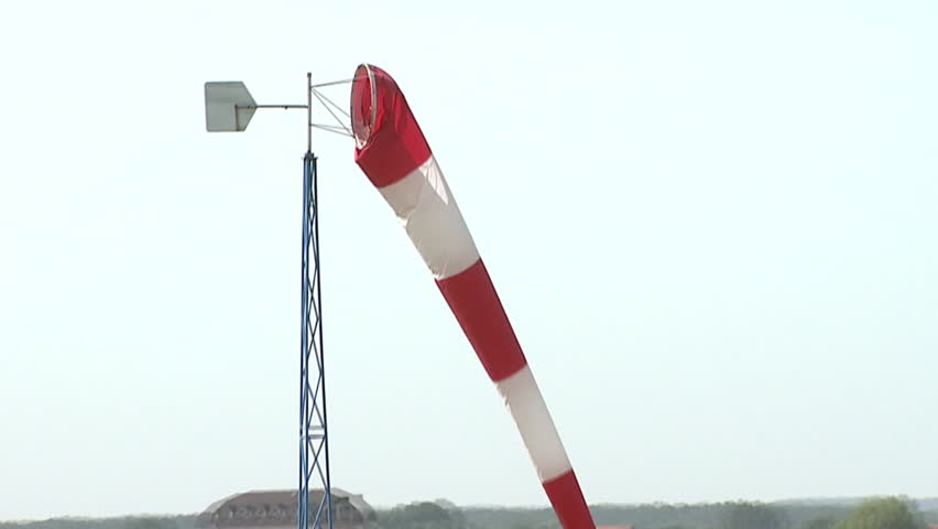 Low and fast aerial of a striped windsock in a field
