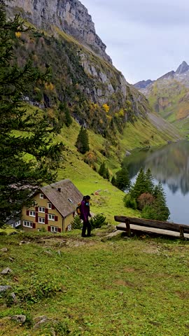 A lone traveler hikes along a scenic path beside a reflective lake, surrounded by majestic mountains and autumn colors. Falensee Switzerland