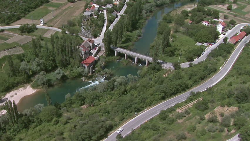 Aerial helicopter shot of a scenic road and a bridge across a river