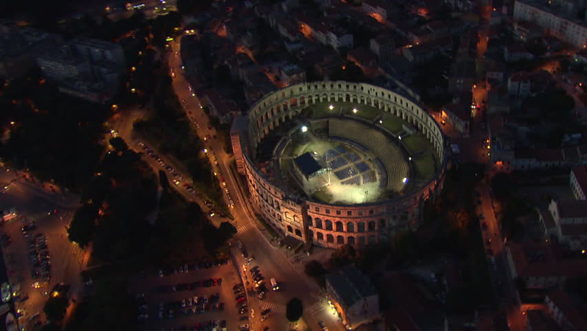 City of Pula and the Arena at night. Aerial helicopter shot.