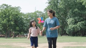 mother and her elementary school daughter cute Asian are playing with colourful windmills in a shady green park together, with different poses and perspectives, they happy holiday activities  - Powered by Shutterstock - Get 15% off with code: PIKWIZARD15