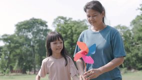 mother and her elementary school daughter cute Asian are playing with colourful windmills in a shady green park together, with different poses and perspectives, they happy holiday activities  - Powered by Shutterstock - Get 15% off with code: PIKWIZARD15