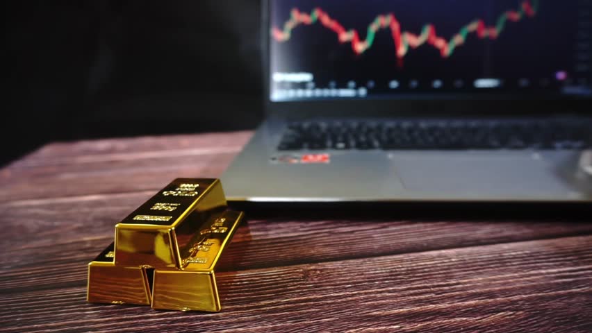 Stacks of gold bars with investment charts in the background. Gold price rise, investment in commodity market trading, etf, risk management concept.