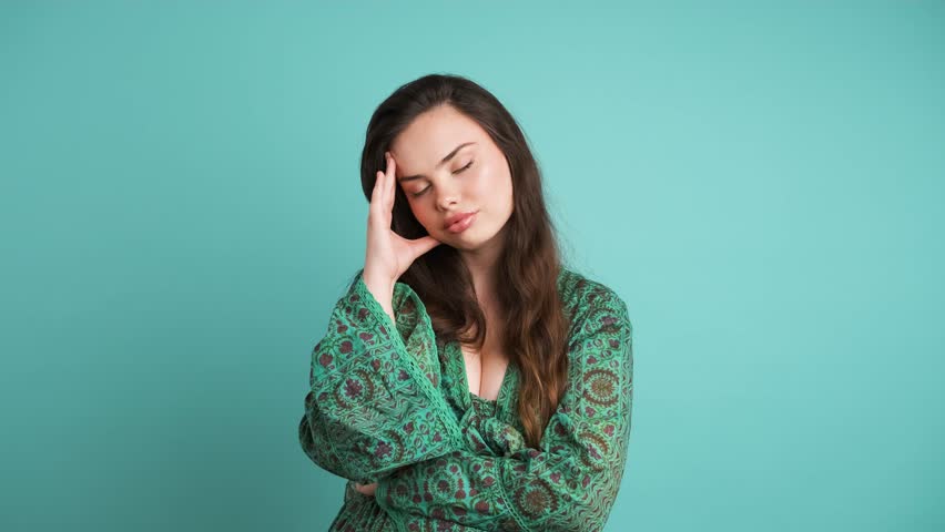 Upset woman suffering from headache in blue studio